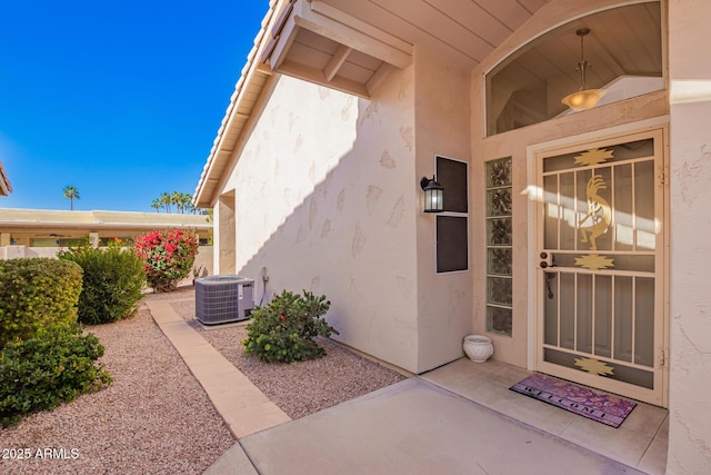 view of exterior entry featuring central AC, a patio, and stucco siding