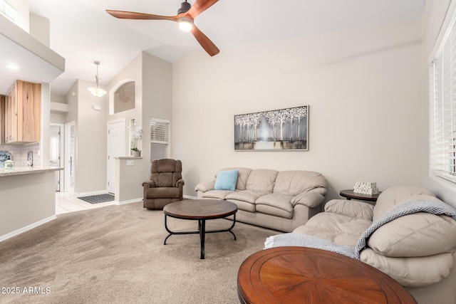 living area with light carpet, ceiling fan, high vaulted ceiling, and baseboards