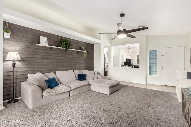 carpeted living room featuring lofted ceiling, ceiling fan, and wood walls