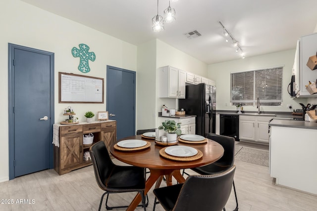 kitchen featuring pendant lighting, sink, white cabinets, light hardwood / wood-style floors, and black appliances