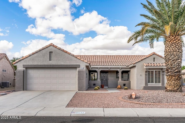 mediterranean / spanish-style home with central AC unit, a garage, concrete driveway, a tiled roof, and stucco siding