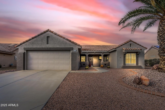 view of front of house featuring a garage, driveway, a tiled roof, and stucco siding