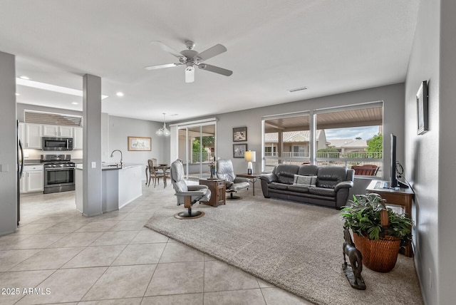 living room featuring light tile patterned floors, ceiling fan with notable chandelier, visible vents, and recessed lighting