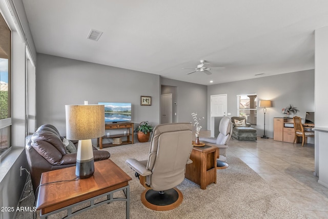 living area with visible vents, ceiling fan, and light tile patterned floors