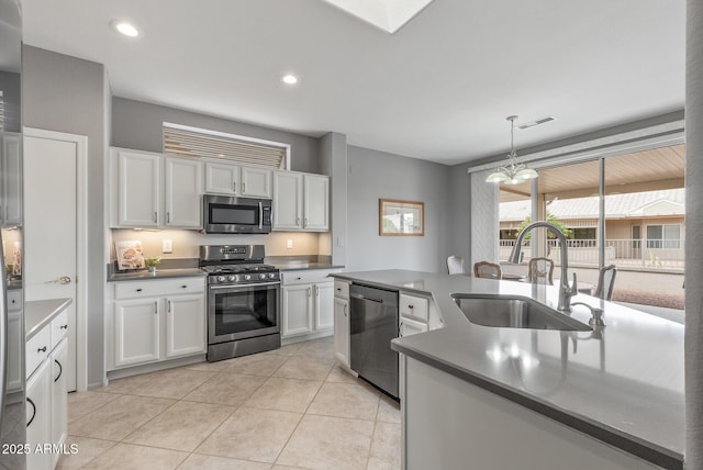 kitchen featuring light tile patterned floors, a sink, white cabinets, appliances with stainless steel finishes, and dark countertops