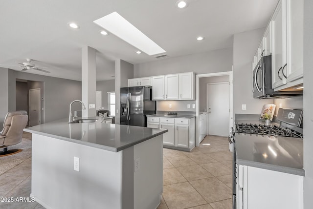 kitchen featuring light tile patterned floors, stainless steel appliances, open floor plan, white cabinetry, and a sink