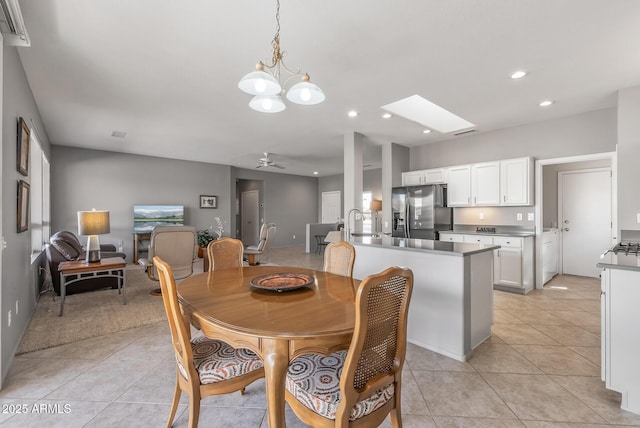 dining space featuring ceiling fan with notable chandelier, recessed lighting, a skylight, and light tile patterned floors