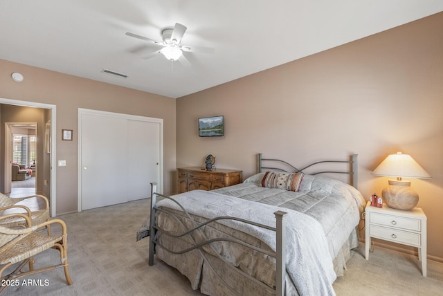 bedroom featuring a ceiling fan, a closet, visible vents, and light carpet