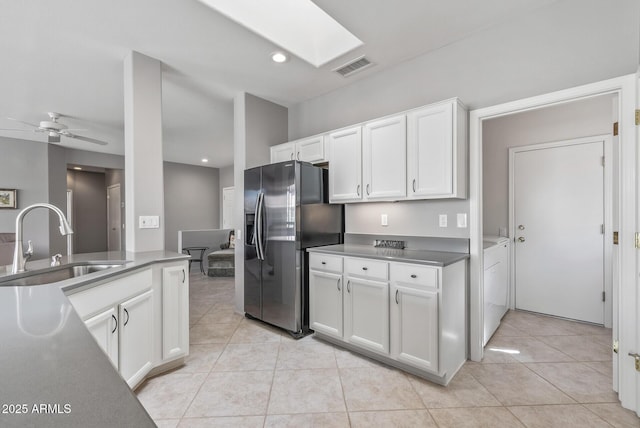 kitchen with separate washer and dryer, a skylight, a sink, white cabinetry, and stainless steel fridge with ice dispenser