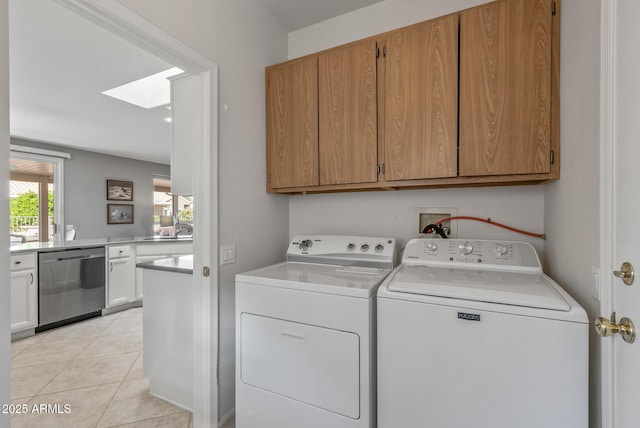 laundry area featuring cabinet space, a skylight, separate washer and dryer, and light tile patterned flooring