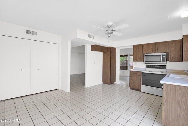 kitchen featuring stainless steel microwave, light countertops, visible vents, and white electric stove