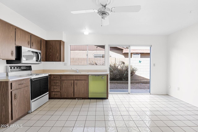 kitchen with white range with electric cooktop, a sink, stainless steel microwave, light countertops, and dishwasher