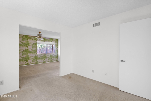 empty room with carpet, baseboards, visible vents, wallpapered walls, and ceiling fan