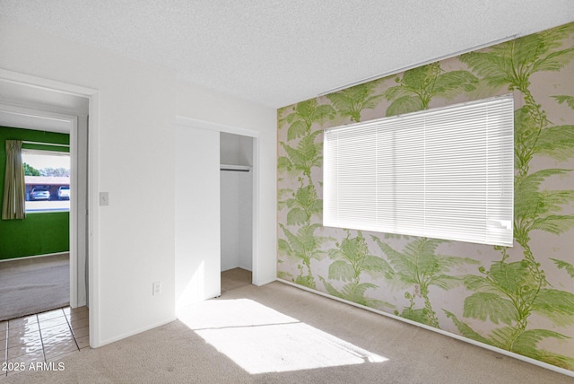 unfurnished bedroom with wallpapered walls, baseboards, carpet flooring, a closet, and a textured ceiling