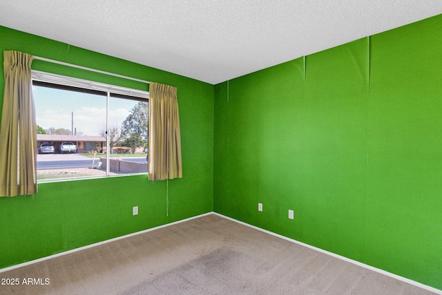 carpeted spare room featuring baseboards and a textured ceiling