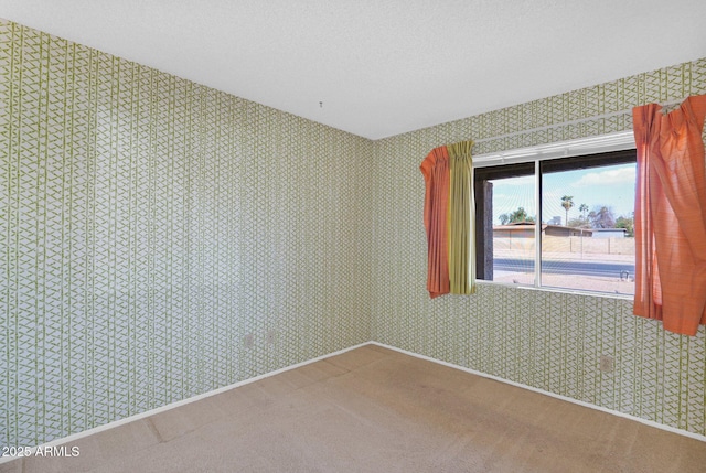 carpeted spare room with wallpapered walls and a textured ceiling