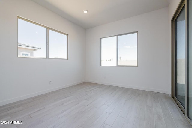 empty room with light wood-type flooring, recessed lighting, and baseboards
