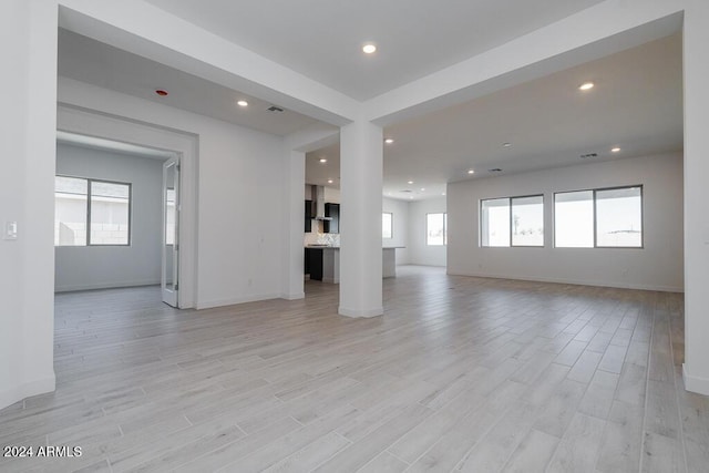 unfurnished living room with baseboards, recessed lighting, light wood-style floors, and a wealth of natural light