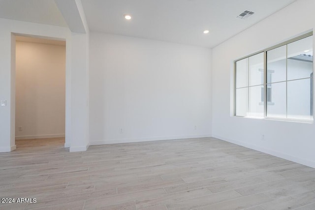 empty room with baseboards, visible vents, and light wood-type flooring