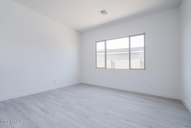 empty room featuring baseboards, light wood-type flooring, and visible vents