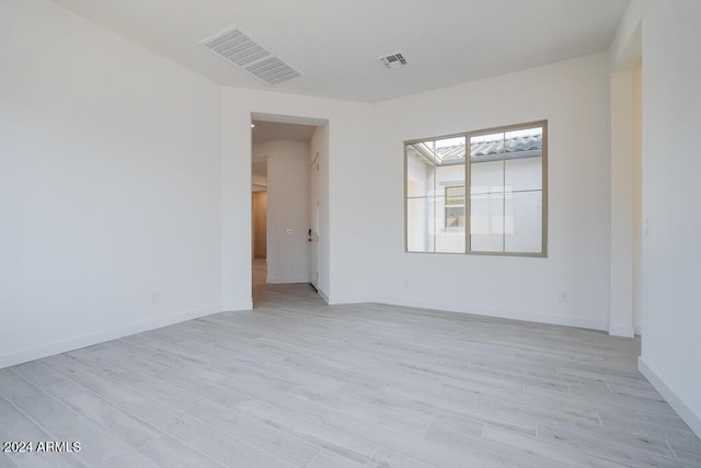 spare room featuring visible vents, baseboards, and light wood-type flooring