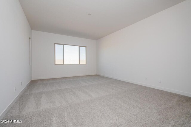 spare room featuring baseboards and light colored carpet