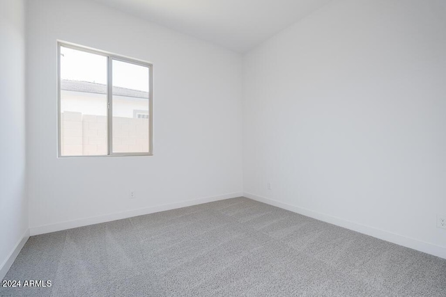 carpeted spare room featuring baseboards