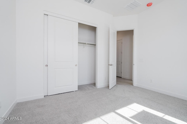 unfurnished bedroom with a closet and light carpet