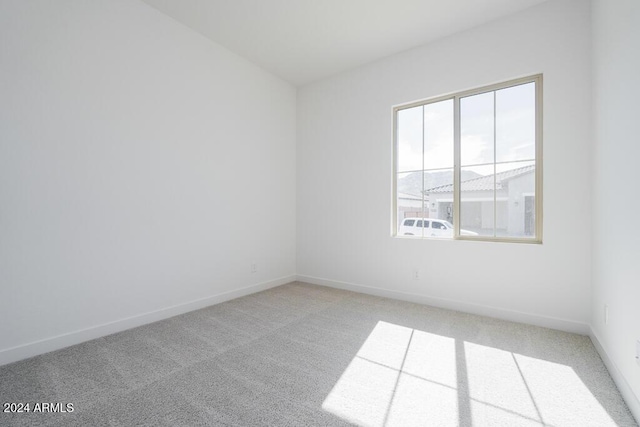 unfurnished room featuring baseboards and light carpet