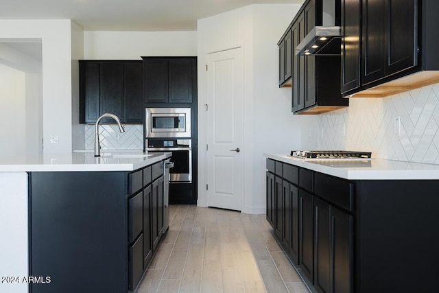 kitchen featuring dark cabinets, stainless steel appliances, and wall chimney exhaust hood