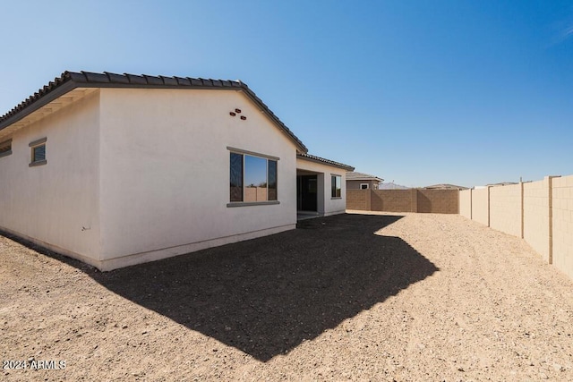 back of property featuring a fenced backyard, stucco siding, and a tiled roof