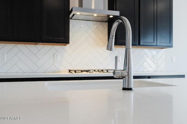 details with light countertops, dark cabinetry, backsplash, and under cabinet range hood