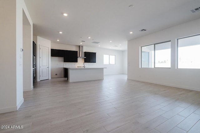 unfurnished living room featuring visible vents, a sink, and light wood-type flooring