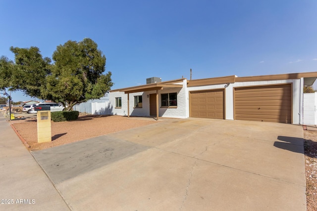 view of front facade featuring cooling unit, driveway, an attached garage, and fence