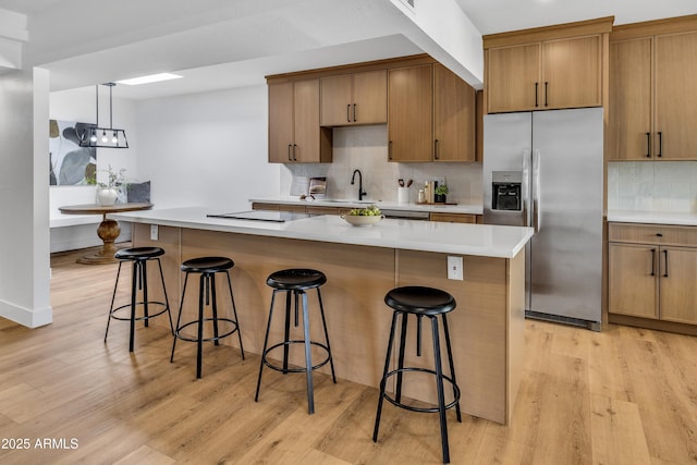 6233 E Pinchot Ave, Scottsdale, AZ 85251 - kitchen with stainless steel fridge with ice dispenser, decorative backsplash, light wood-type flooring, brown cabinetry, and a kitchen bar