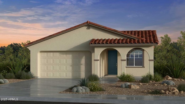 mediterranean / spanish home with an attached garage, driveway, a tile roof, and stucco siding