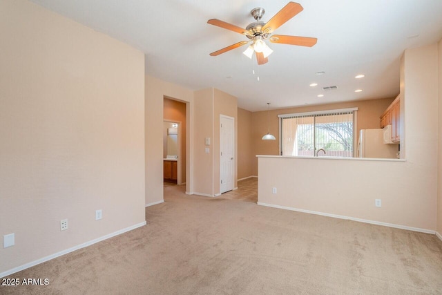 carpeted spare room featuring ceiling fan and sink