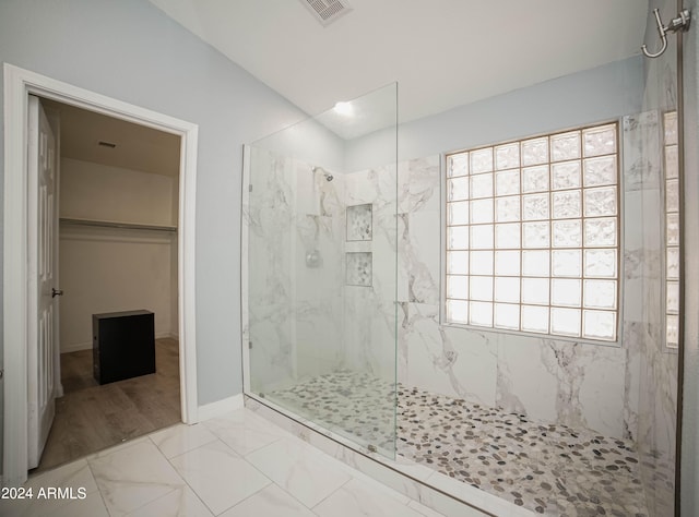 bathroom with hardwood / wood-style flooring, a tile shower, and a healthy amount of sunlight