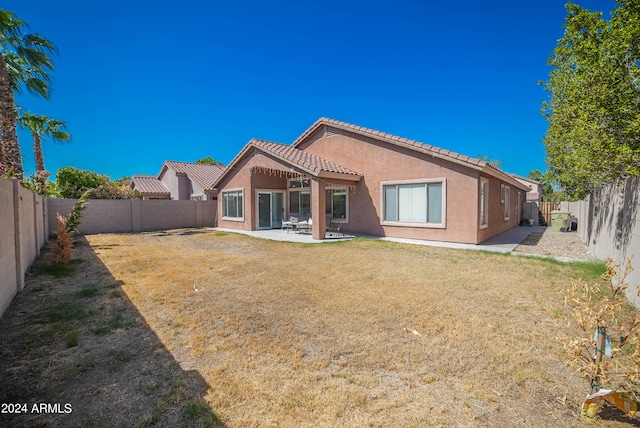 rear view of property featuring a lawn and a patio