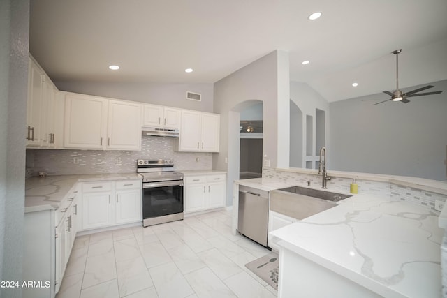 kitchen featuring white cabinets, lofted ceiling, kitchen peninsula, stainless steel appliances, and light stone countertops