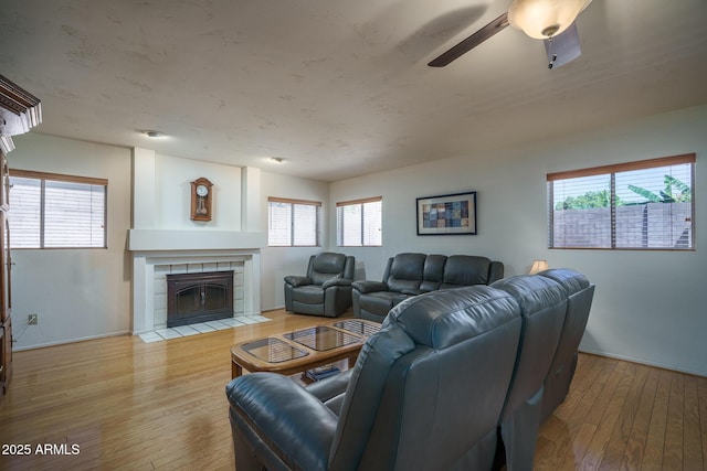 5596 W Mercer Ln, Glendale, AZ 85304 - living room featuring hardwood / wood-style flooring, ceiling fan, a tile fireplace, and healthy amount of natural light