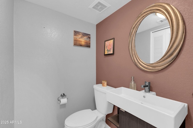 half bathroom with visible vents, toilet, and a sink