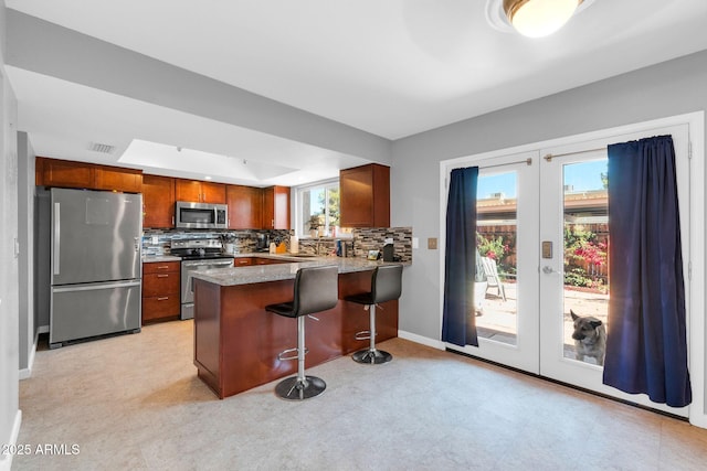 kitchen featuring light floors, appliances with stainless steel finishes, a peninsula, and french doors