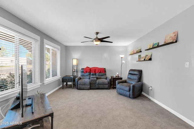 carpeted living area with baseboards and a ceiling fan