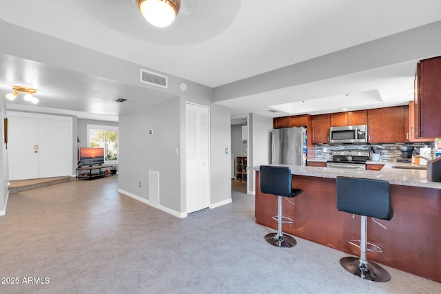 kitchen with visible vents, a sink, backsplash, stainless steel appliances, and light floors