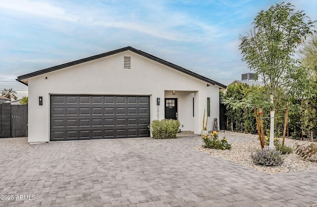 ranch-style home featuring stucco siding, decorative driveway, a garage, and fence