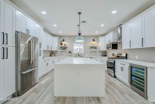 kitchen with beverage cooler, open shelves, a sink, appliances with stainless steel finishes, and wall chimney exhaust hood