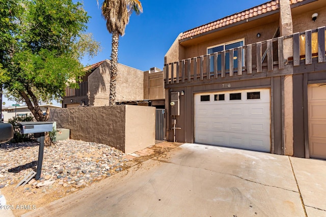 view of front facade with a garage, mansard roof, concrete driveway, a tile roof, and stucco siding