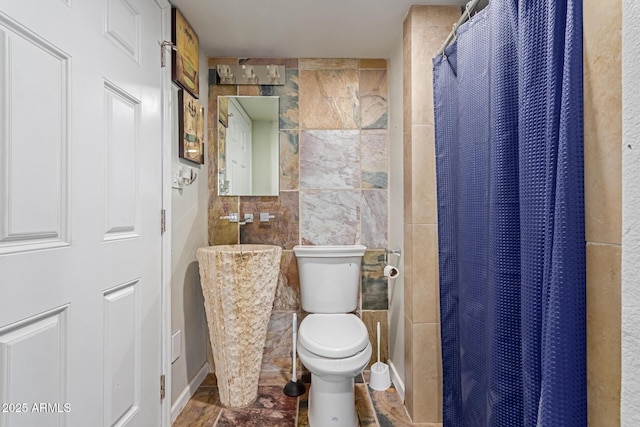 full bath with a shower with curtain, tile walls, and toilet