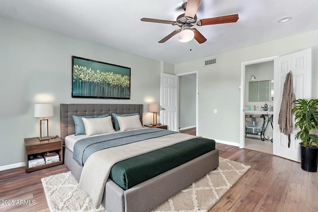 bedroom featuring a ceiling fan, visible vents, baseboards, and wood finished floors